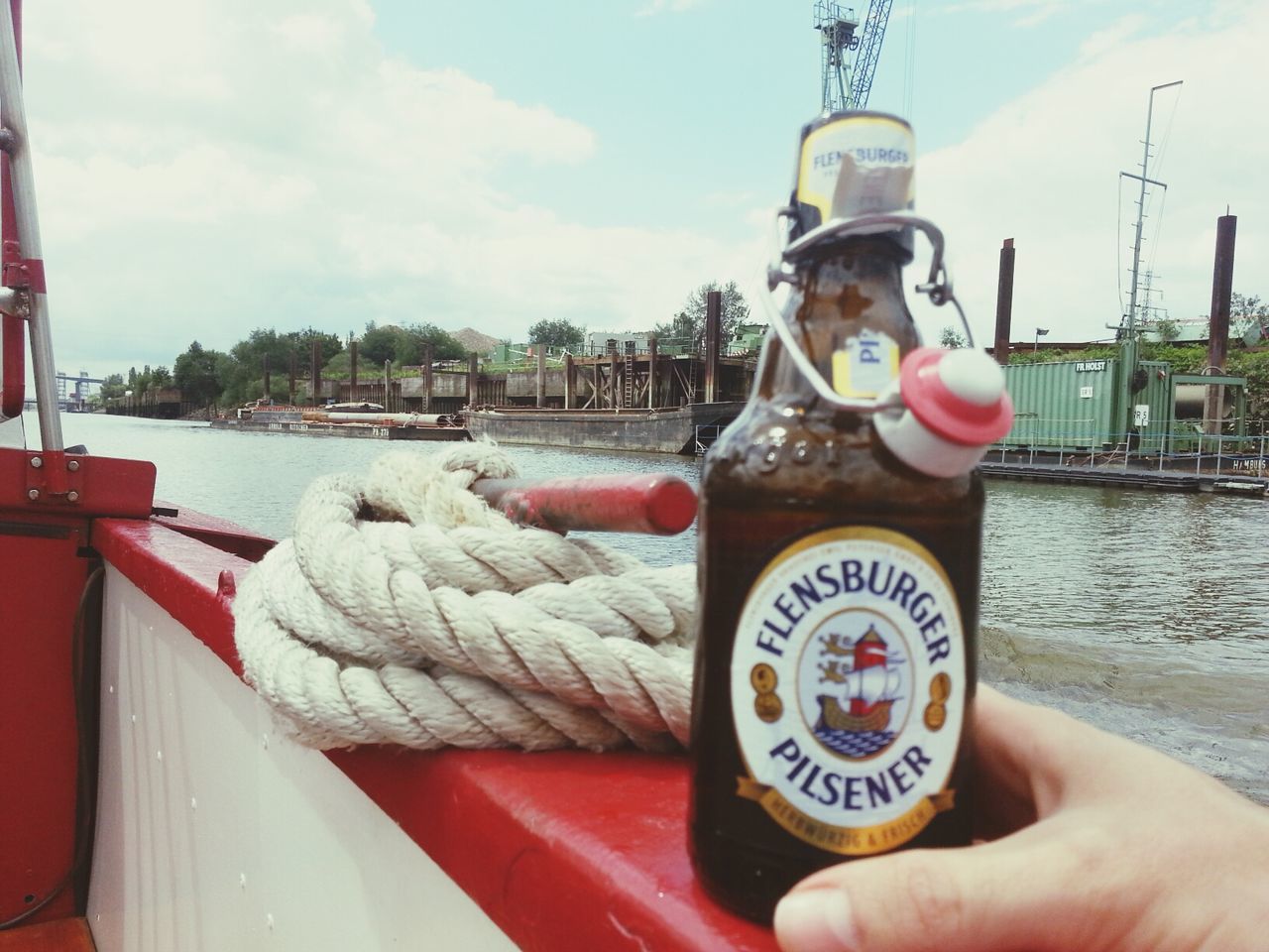 nautical vessel, transportation, sky, water, part of, mode of transport, cropped, person, text, holding, boat, sea, western script, focus on foreground, day, harbor, communication, metal