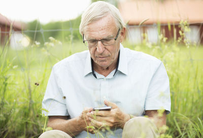 Senior man text messaging on mobile phone while sitting in yard