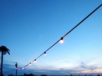 Low angle view of birds on cable against sky