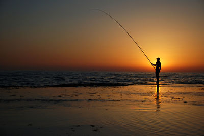 Fisherman at the sea during a sunset