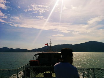 Rear view of woman photographing on sea against sky during sunset