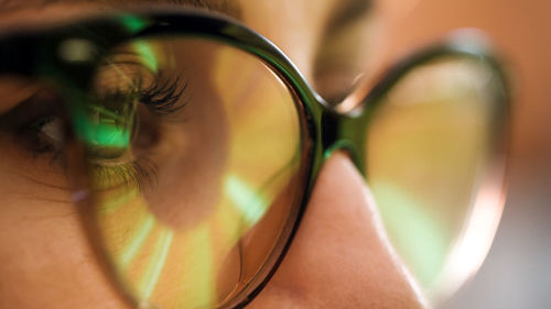 Close up of female hacker eyes. reflection of screen computer lights on programmer eyeglasses.