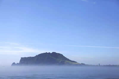 Scenic view of sea and mountains against blue sky