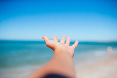 Cropped hand of woman against sea