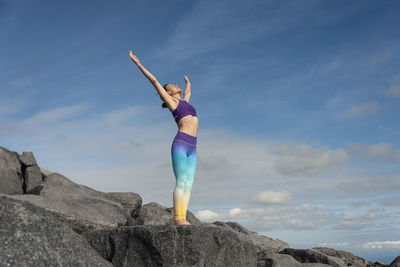 Low angle view of woman jumping against sky