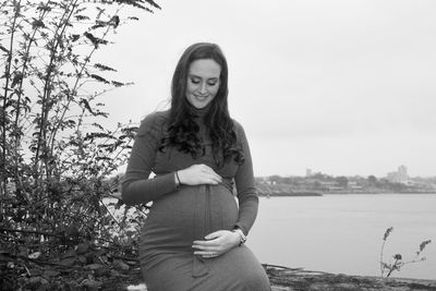 Portrait of young woman standing against trees