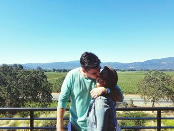 Young couple standing against clear sky