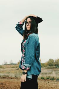 Full length of young woman standing against sky