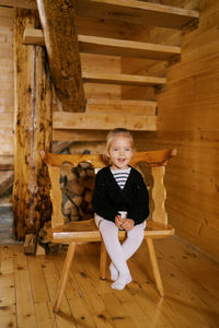 Portrait of young woman sitting on wooden wall