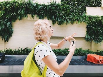 Woman with arms raised standing against plants