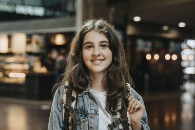 Portrait of smiling girl with backpack at station