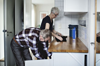 Side view of retired senior couple working in bathroom at home