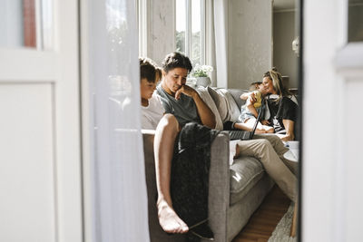 Parents sitting with children on sofa at home