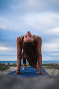 Rear view of woman sitting on beach against sky