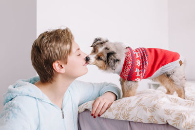 Young woman and dog sitting on bed at home