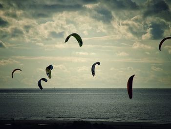 Seagulls flying over sea against cloudy sky