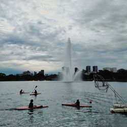 People in water fountain against sky