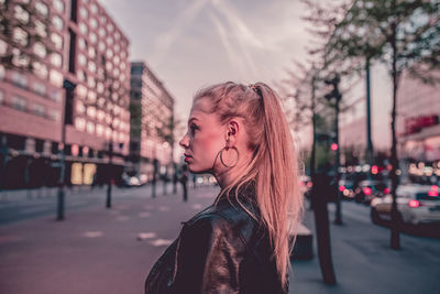 Side view of woman standing on street in city