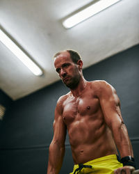 Shirtless fit young man working out in a cage at indoors gym