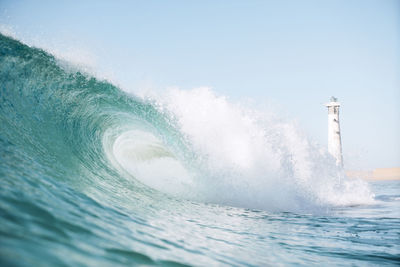 Low angle view of waves in sea splashing against clear sky