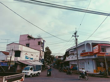 Cars on road by buildings in city against sky