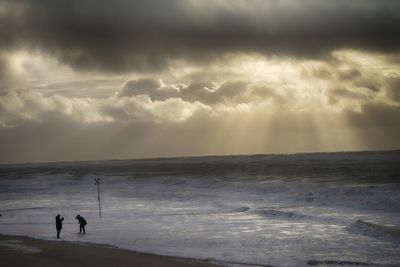 Silhouette people on beach against sky