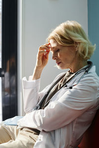 Exhausted doctor with blond hair sitting in clinic