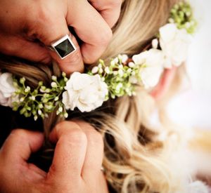 Cropped image of woman hands arranging floral crown in bride hair during wedding
