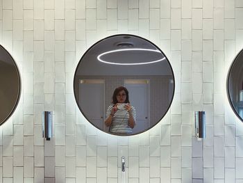 Reflection of woman taking mirror selfie in bathroom