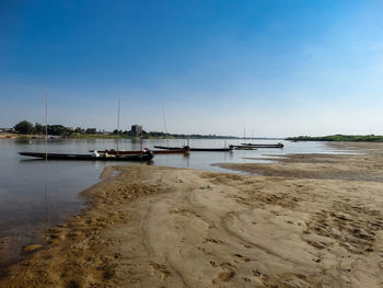 Sailboats moored in sea against sky