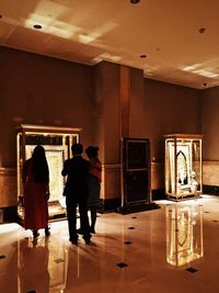 Rear view of people standing in illuminated room