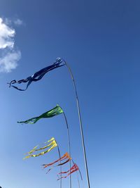 Low angle view of flags against blue sky