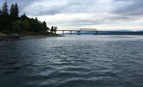 Bridge over river against cloudy sky