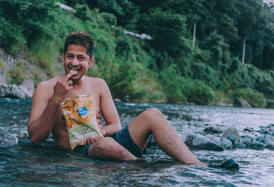 Young man sitting by river