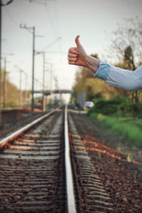 Midsection of person on railroad track against sky