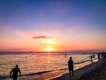 Silhouette people on beach against sky during sunset