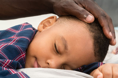 Father touching head of his sleeping mixed race son