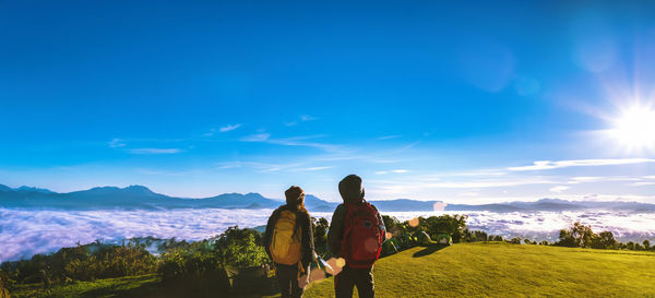 Rear view of woman standing on mountain against sky