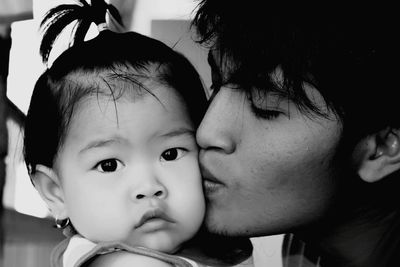 Close-up of father kissing baby girl at home