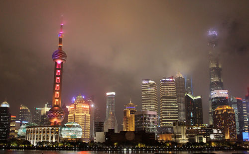 Illuminated buildings in city against sky at night