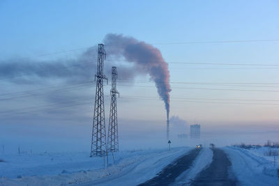 Smoke emitting from chimney against sky during winter