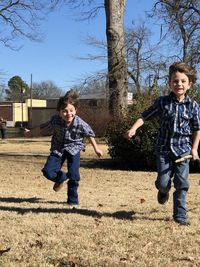 Full length of siblings running on field