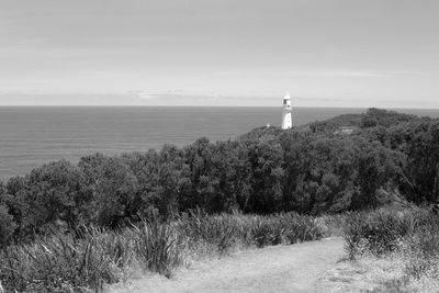 Lighthouse by sea against sky