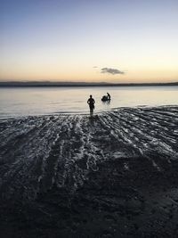 Silhouette male friends with jet boat in sea during sunset