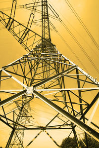 Low angle view of electricity pylon against sky during sunset