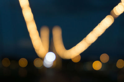 Defocused image of hand holding illuminated lights at night