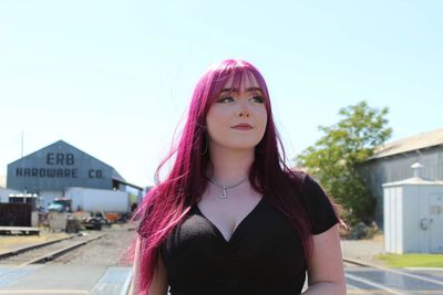 Portrait of young woman standing against sky