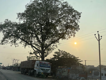 Cars on street against sky during sunset