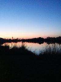 Scenic view of lake against clear sky at sunset