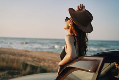 Woman wearing hat on beach against sky